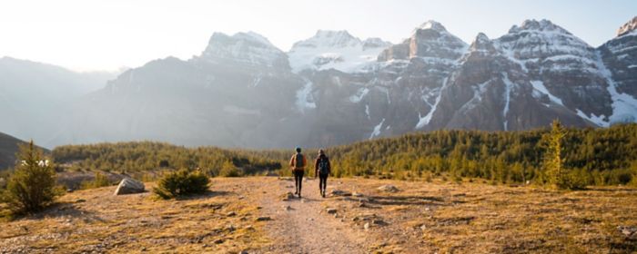 Fotografia de dos personas caminando un sendero hacia la montaña